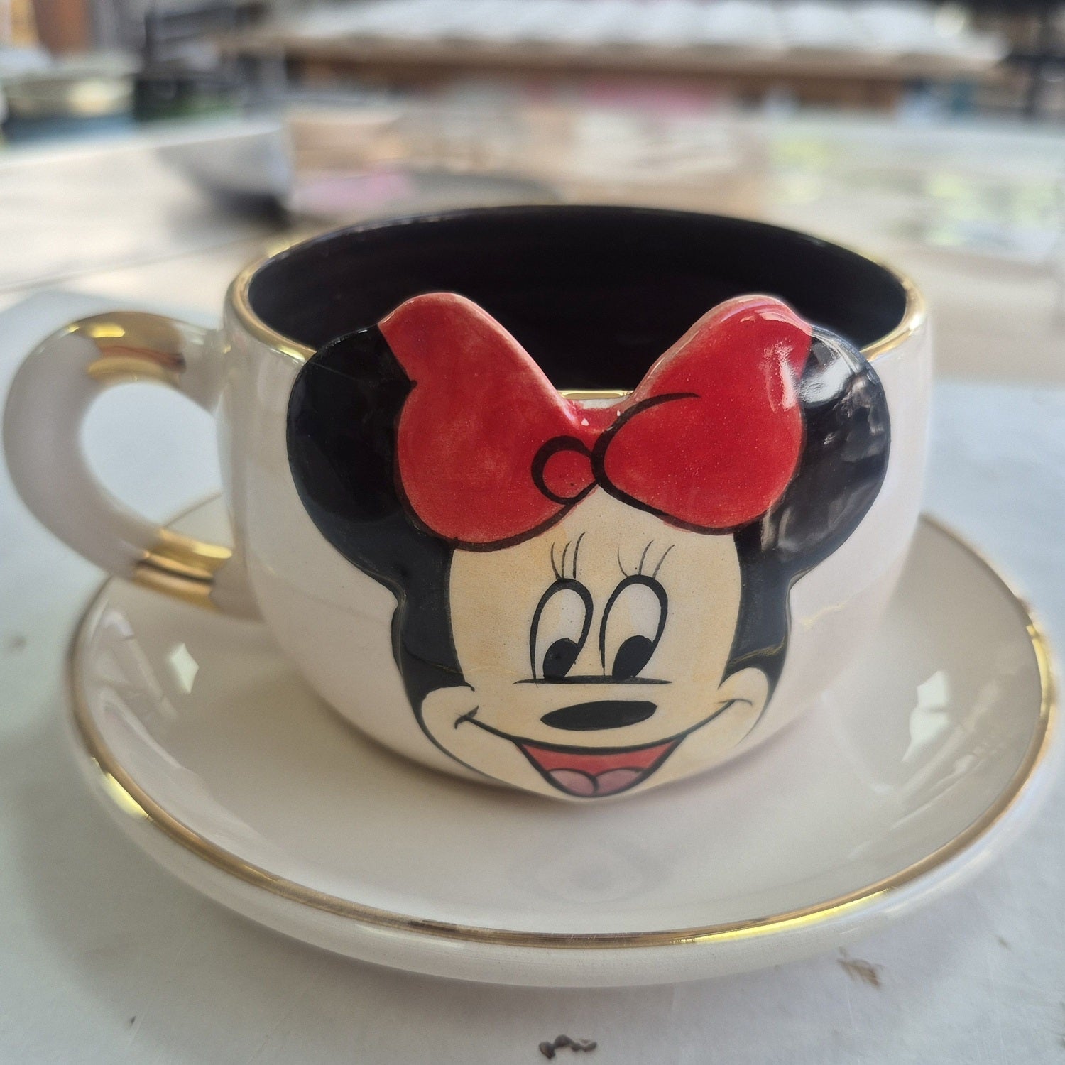Minnie Mouse tea mug with red bow print, black interior and gold-accent handle