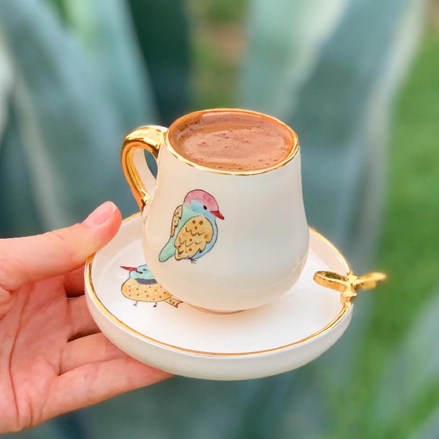 Coffee cup with saucer, white ceramic with gold rim, colorful bird design, gold cross detail