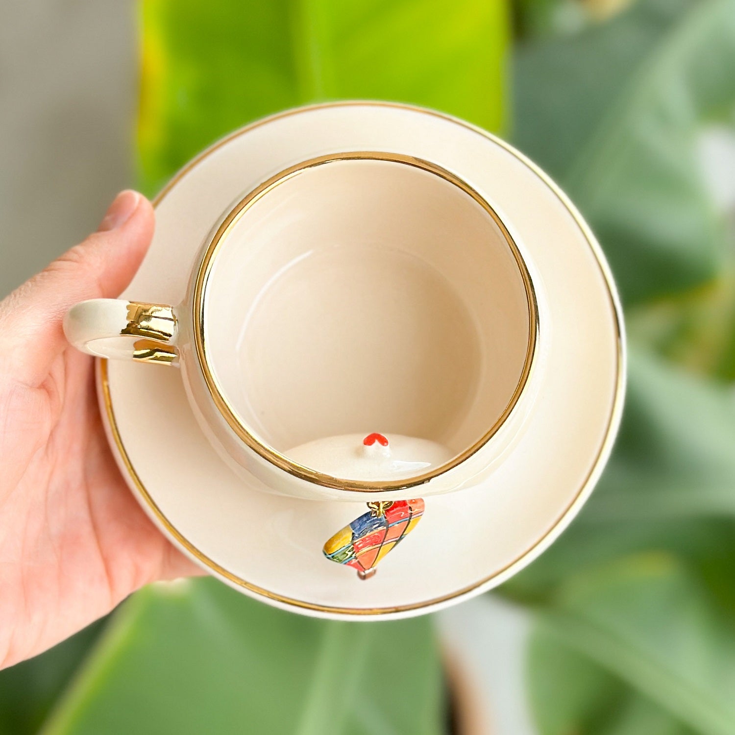Cream ceramic mug top view with gold rim; hot air balloon graphic on inner base