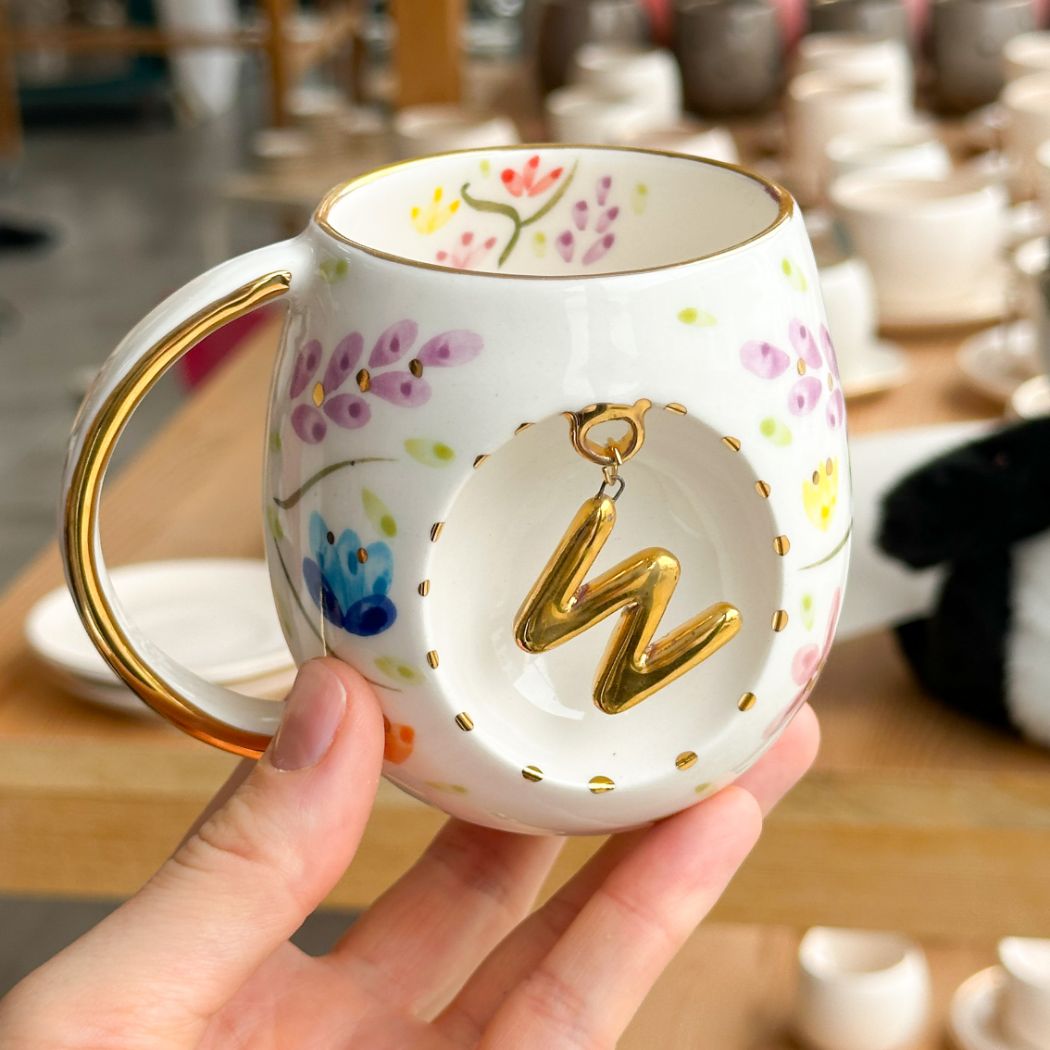 Porcelain letter mug with gold handle and spring floral design, featuring gold letter charm
