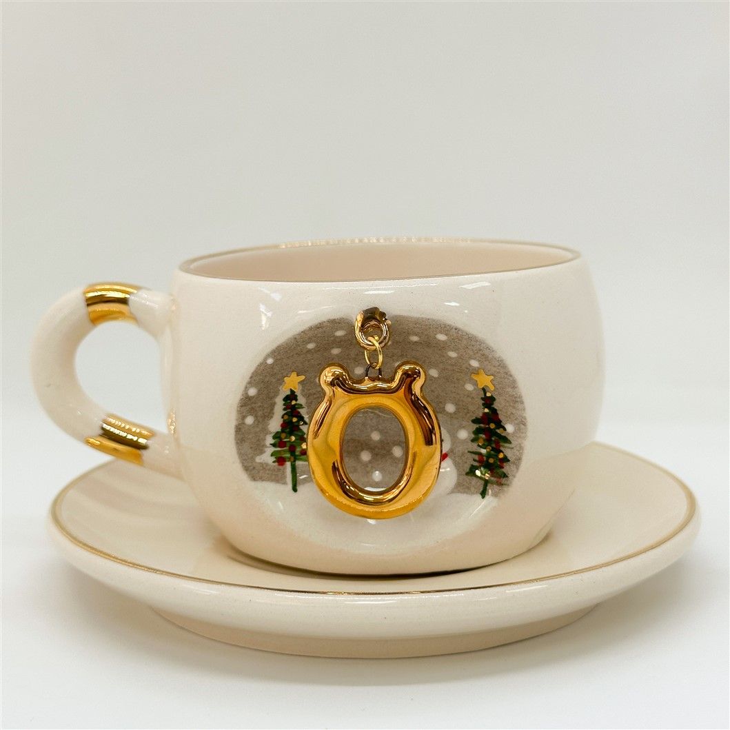 Porcelain tea cup and saucer, white with gold rim and handle; winter O letter motif