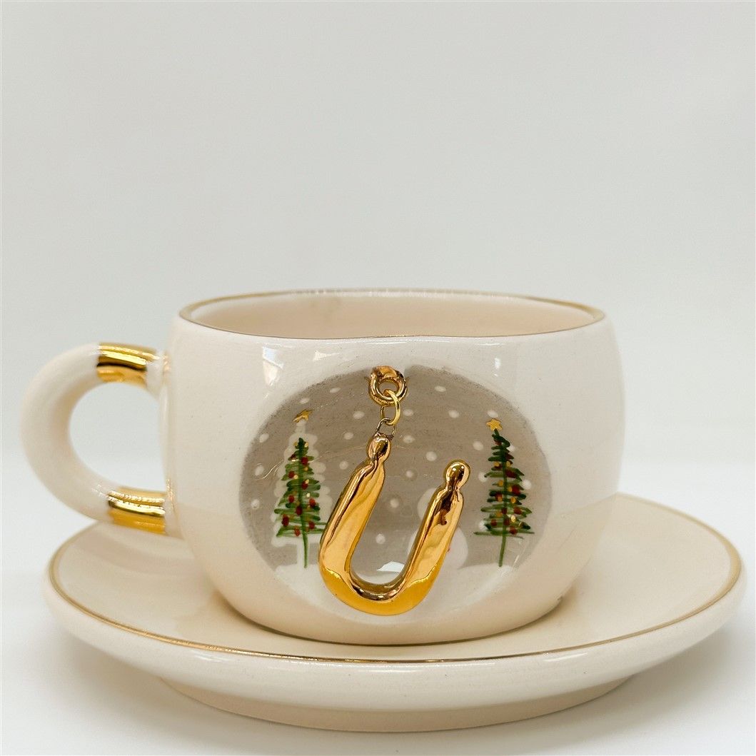 Porcelain tea cup and saucer, gold handle, letter U charm with tree accents