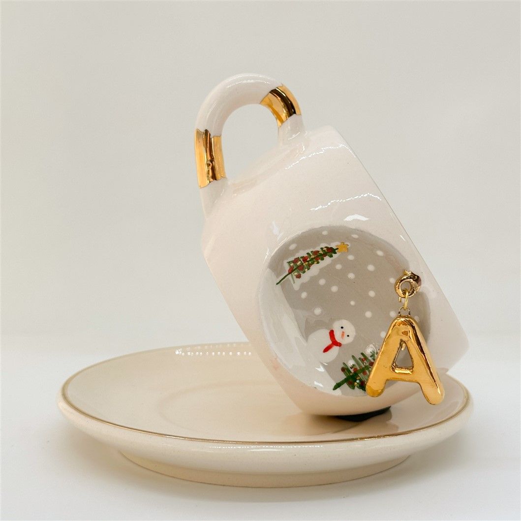 Porcelain tea cup and saucer, gold handle, letter A charm with snowman and trees