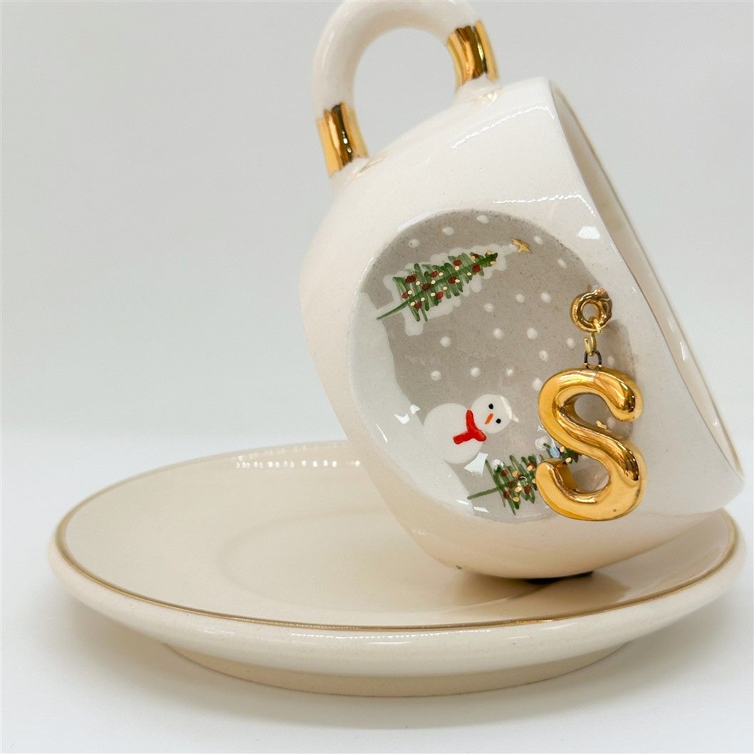 Porcelain tea cup and saucer with gold handle, hanging winter letter charm, snowman and trees