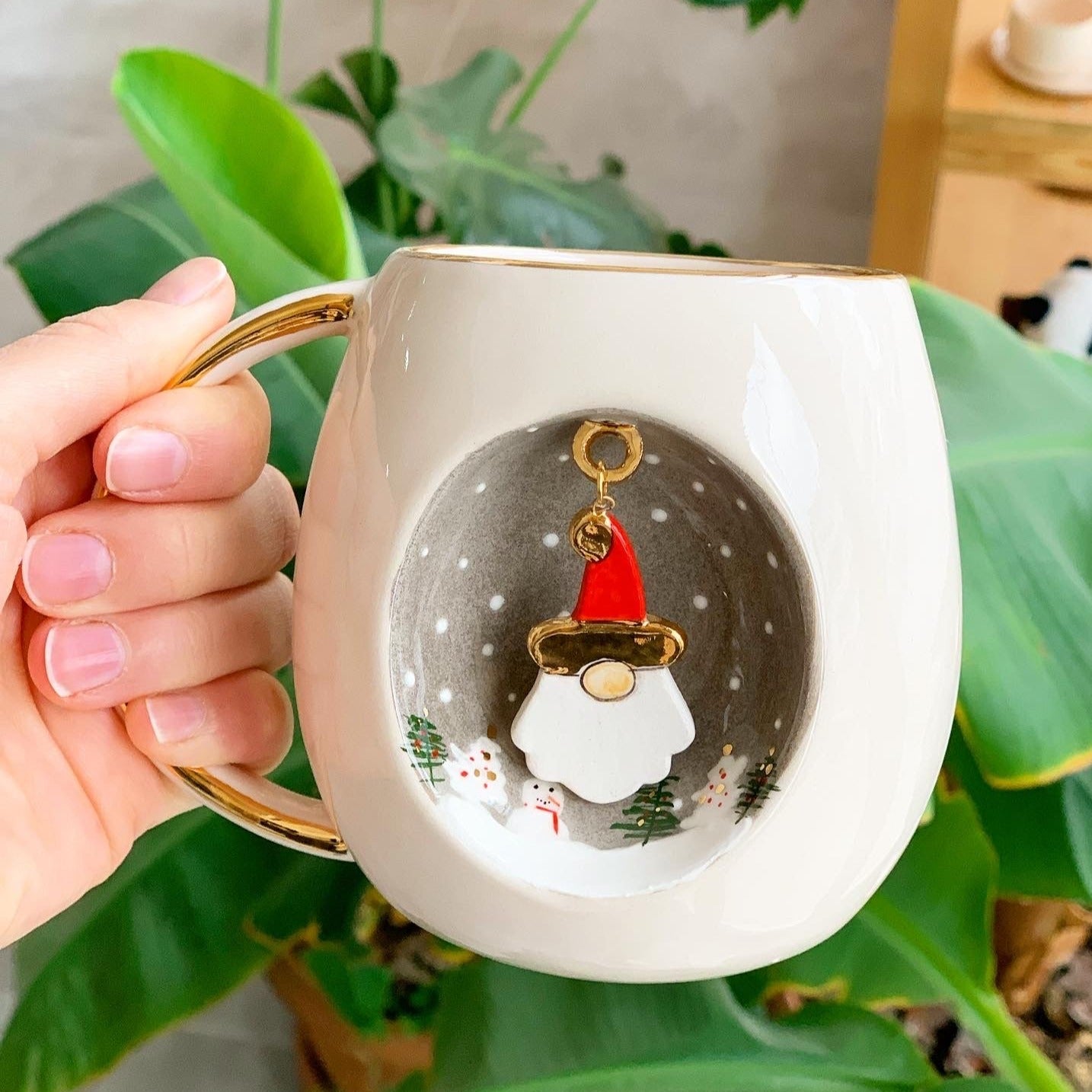 White mug with gold handle and rim, Father Christmas figure in a snowy circle