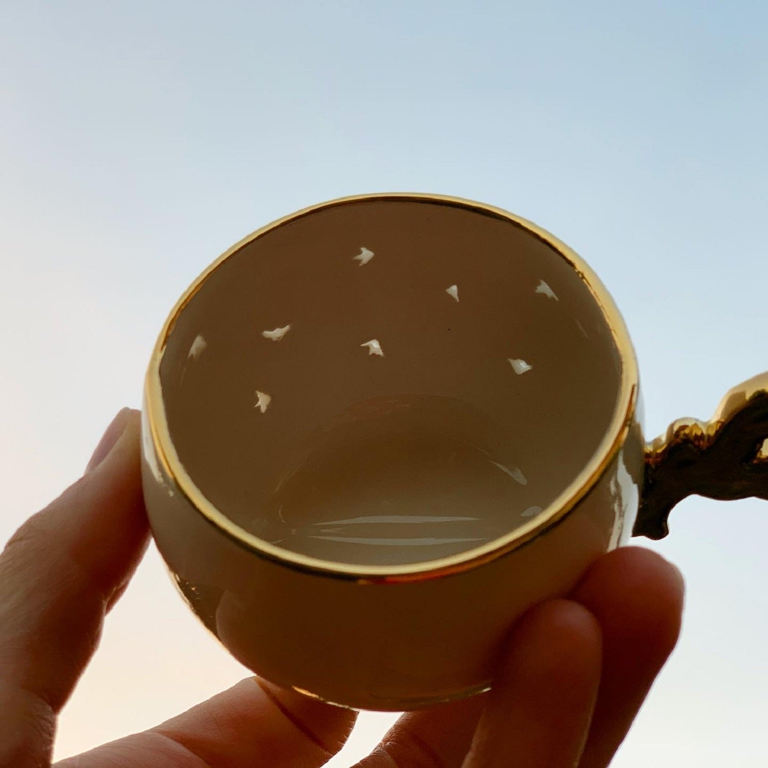 Transparent coffee cup with gold rim and small bird motifs, viewed from top