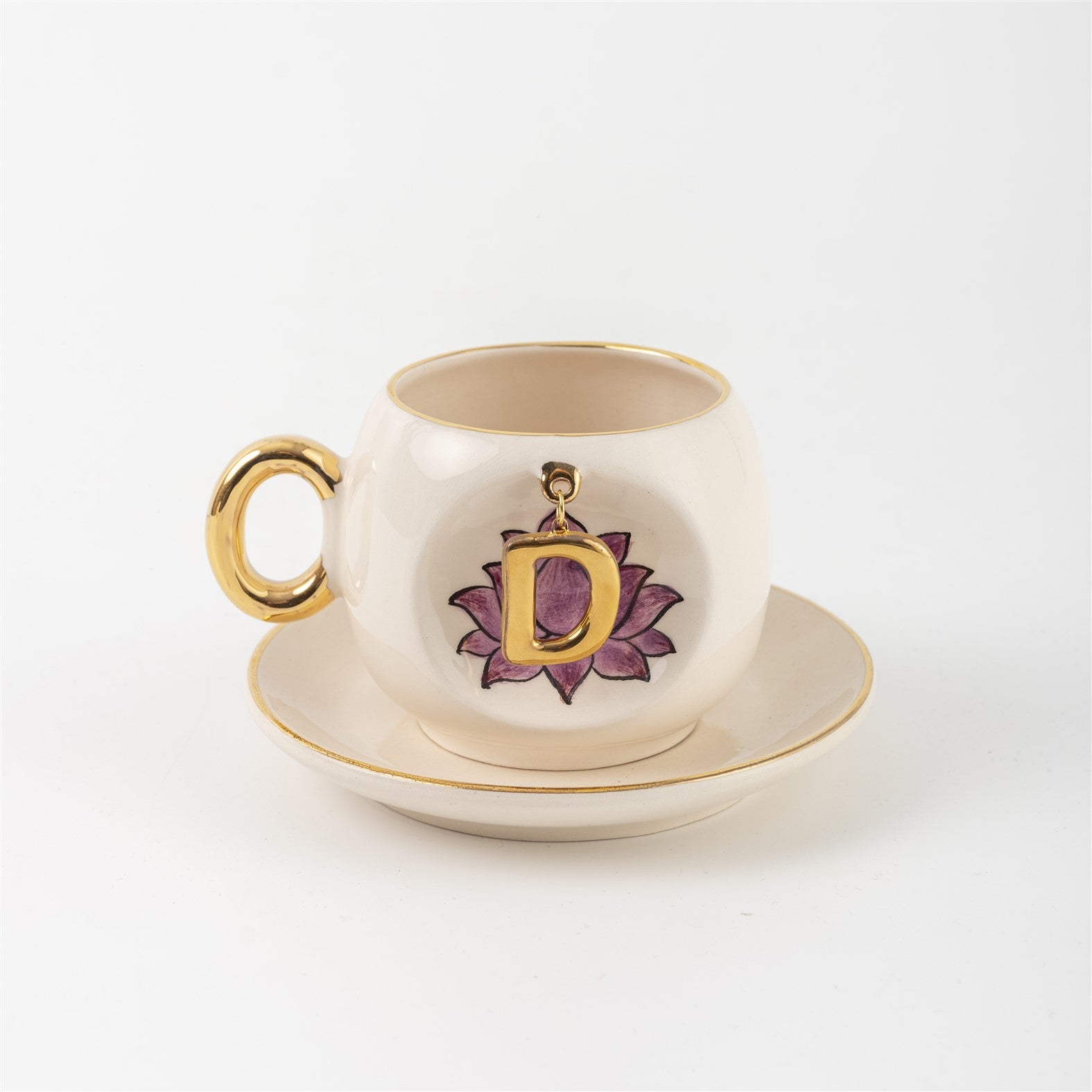 Ceramic coffee cup and saucer with gold handle, lotus letter D emblem on front