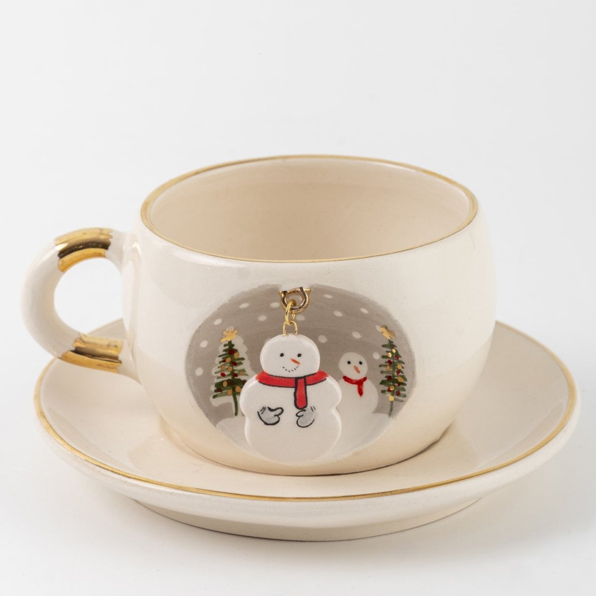 White tea cup and saucer with gold trim, snowman graphic and hanging charm