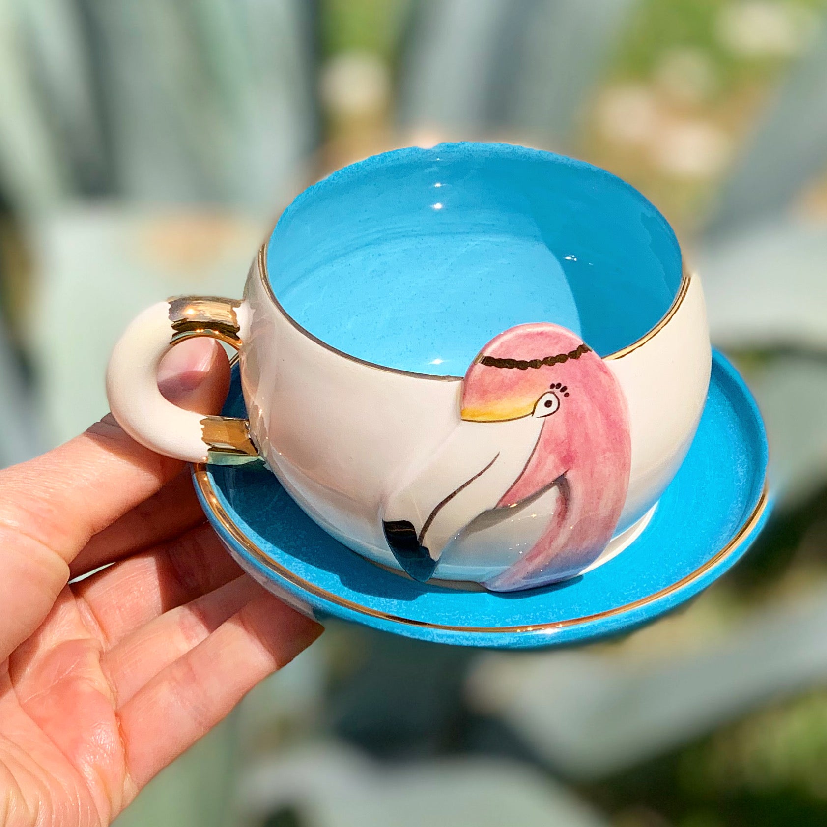 Flamingo tea mug on blue saucer, white body with pink flamingo artwork