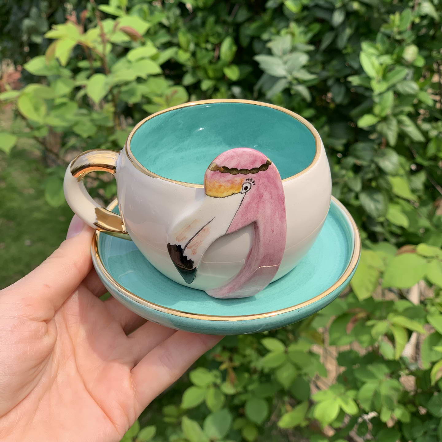 Nile green tea mug with handle, flamingo illustration, on matching saucer