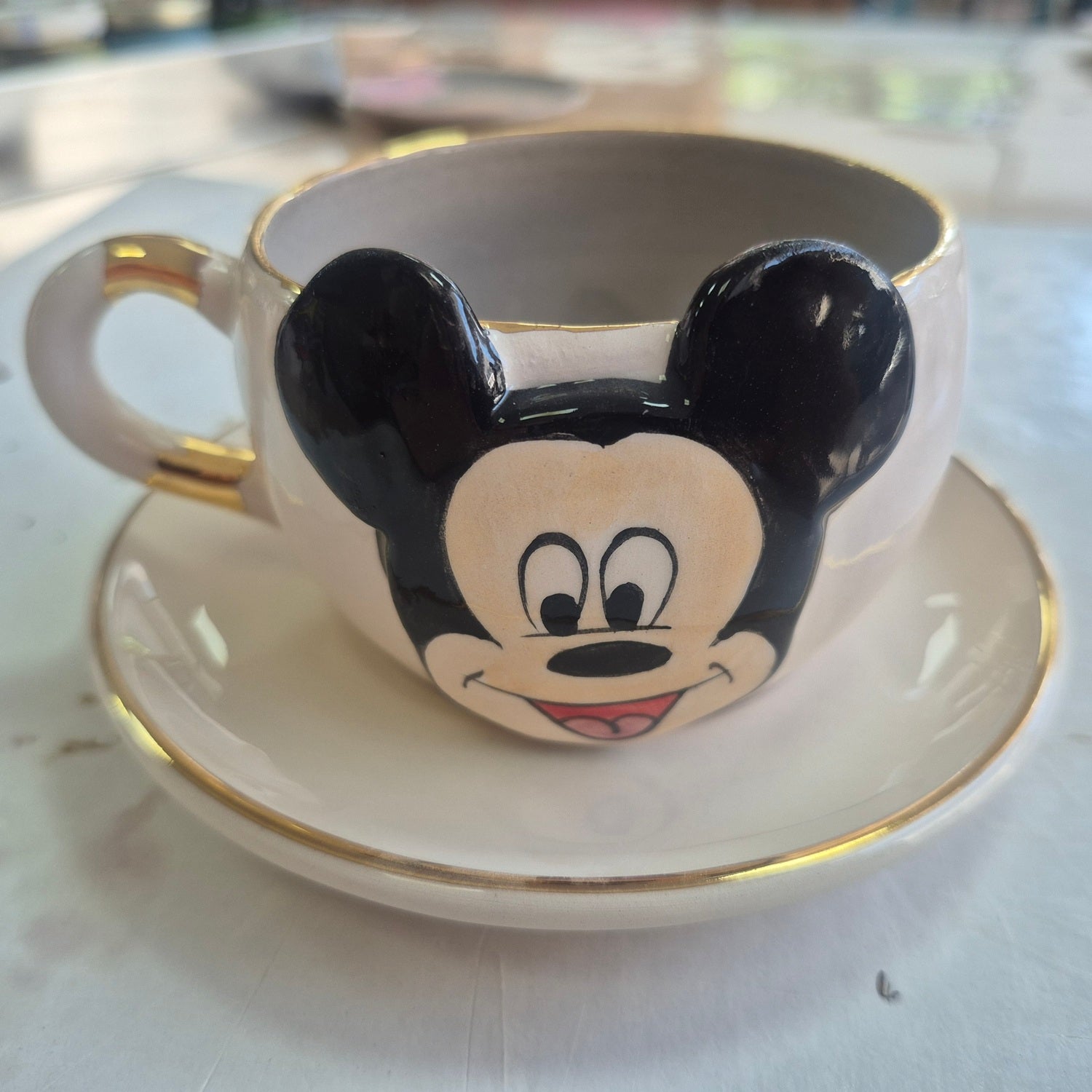 Gray ceramic Mickey Mouse tea cup with gold rim and saucer, Mickey face on front