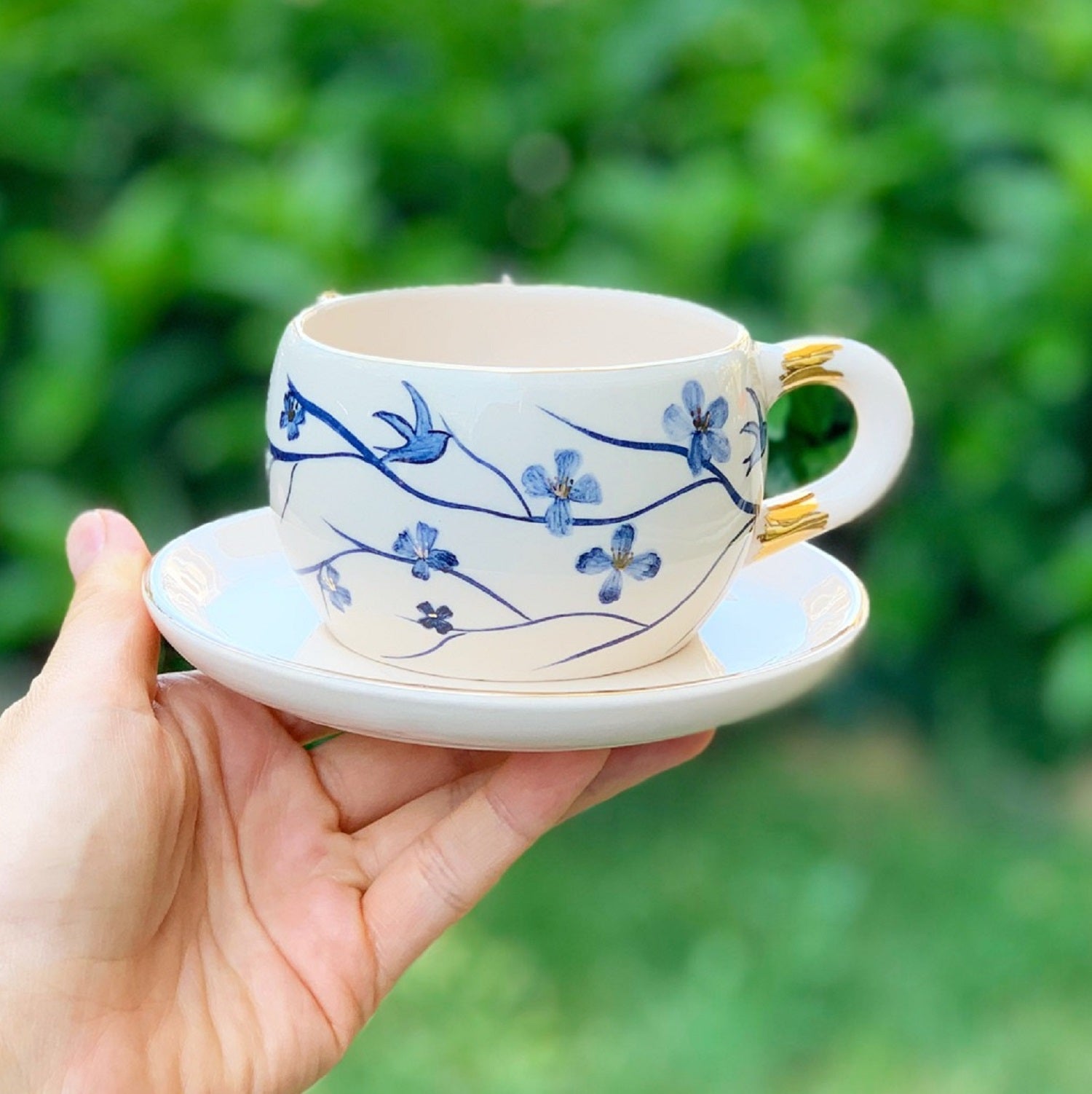 Porcelain mug with blue floral branch pattern and gold handle detail