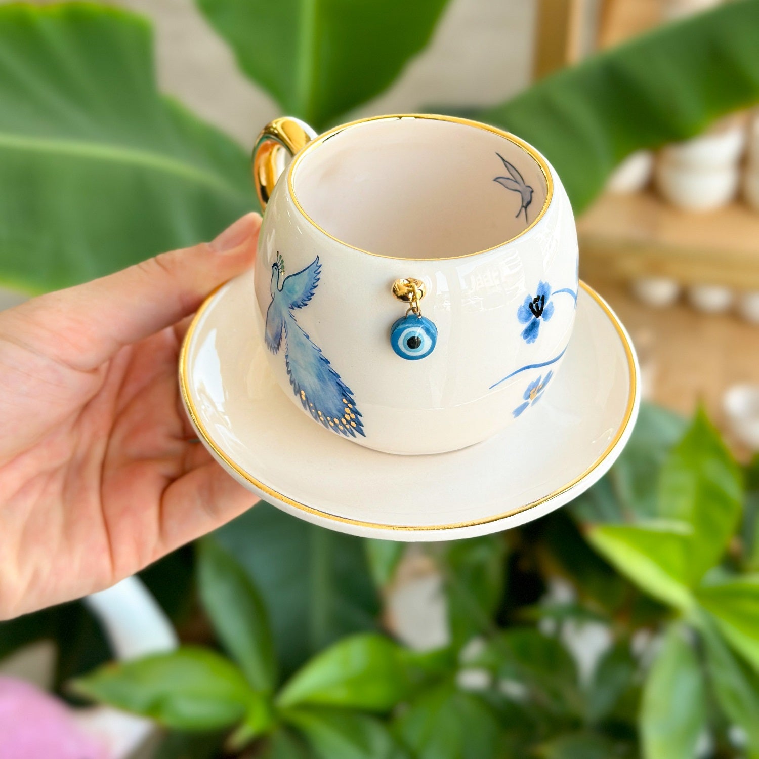 Coffee cup and saucer, white with blue bird and eye motif, gold-edged saucer