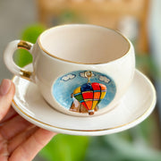 Cream ceramic hot air balloon mug with gold rim and balloon graphic on cup front