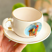 Cream hot air balloon mug with gold trim and balloon graphic, paired with matching saucer