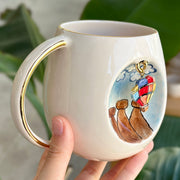 Ceramic mug with gold handle, showing a hot-air balloon dog illustration on the side