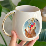 Ceramic mug with gold handle and hot-air balloon dog illustration on the front