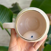 Ceramic mug interior view with small blue drop detail at the bottom