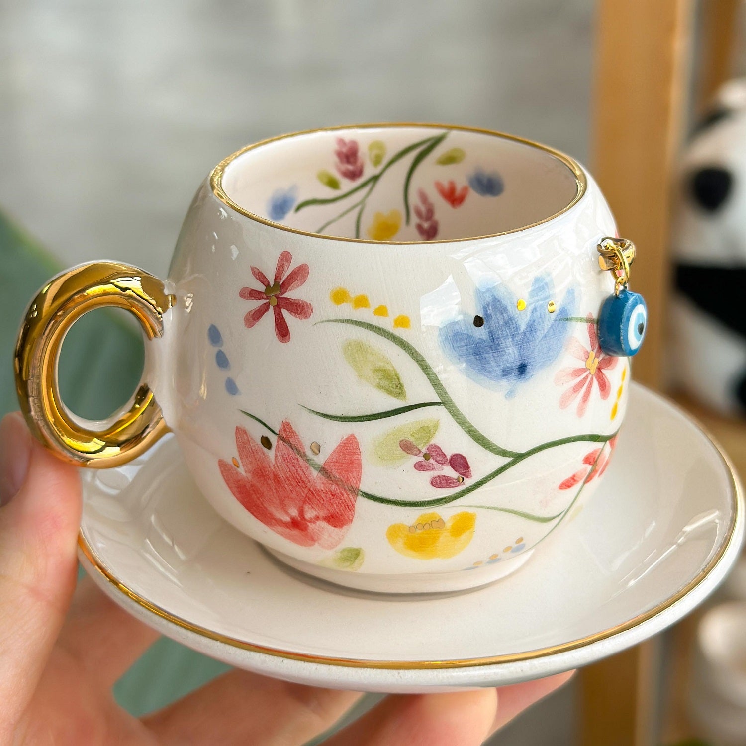 Porcelain coffee cup and saucer set with floral pattern and gold handle accents