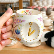 Porcelain letter mug with gold handle and spring floral design, with gold letter charm
