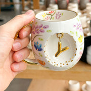 Porcelain letter mug with gold handle and spring floral design, featuring gold letter charm