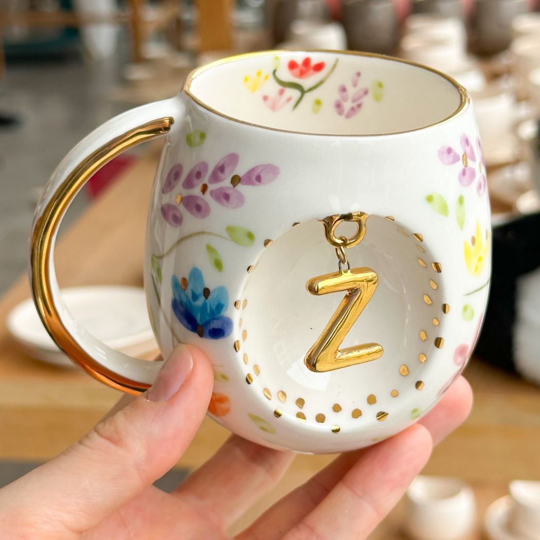 Porcelain letter mug with gold handle and spring floral design, featuring gold letter charm