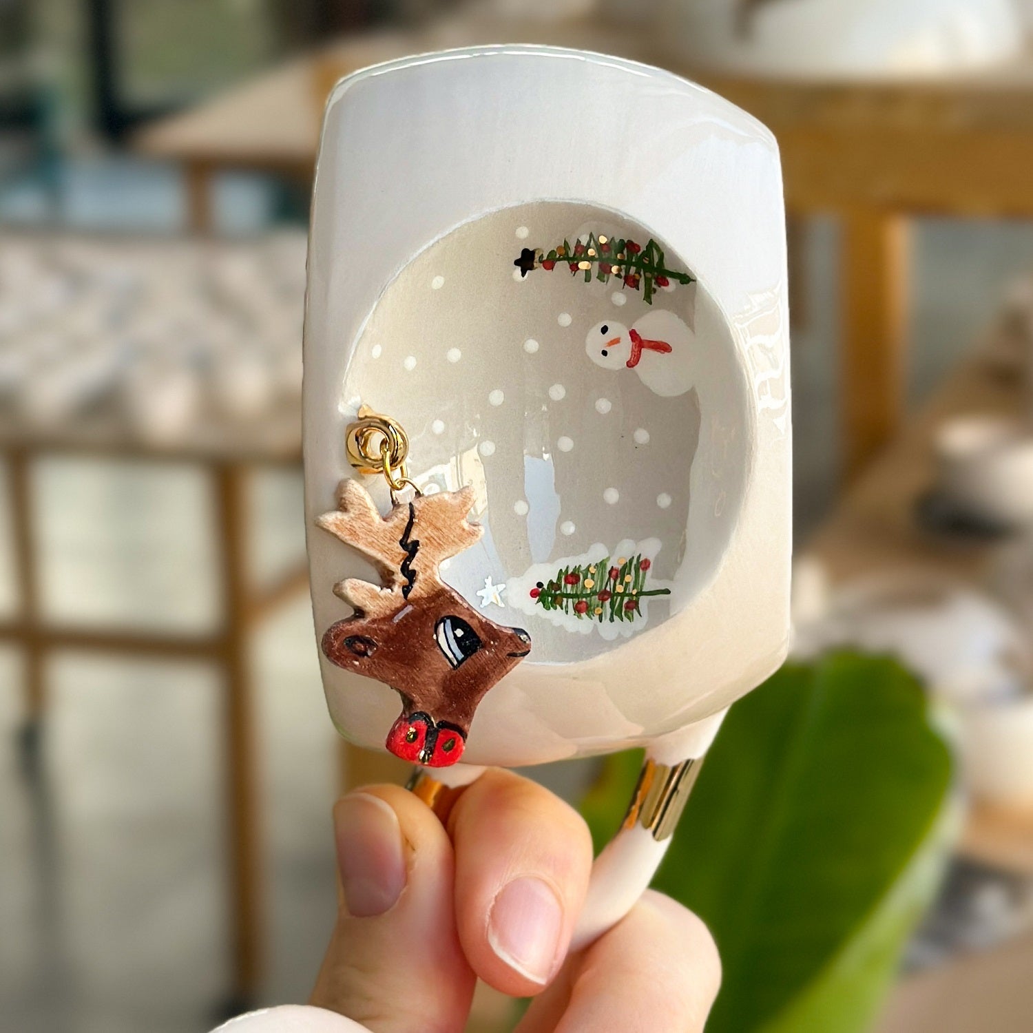 White deer mug with gold-toned charm and reindeer illustration on side; empty cup