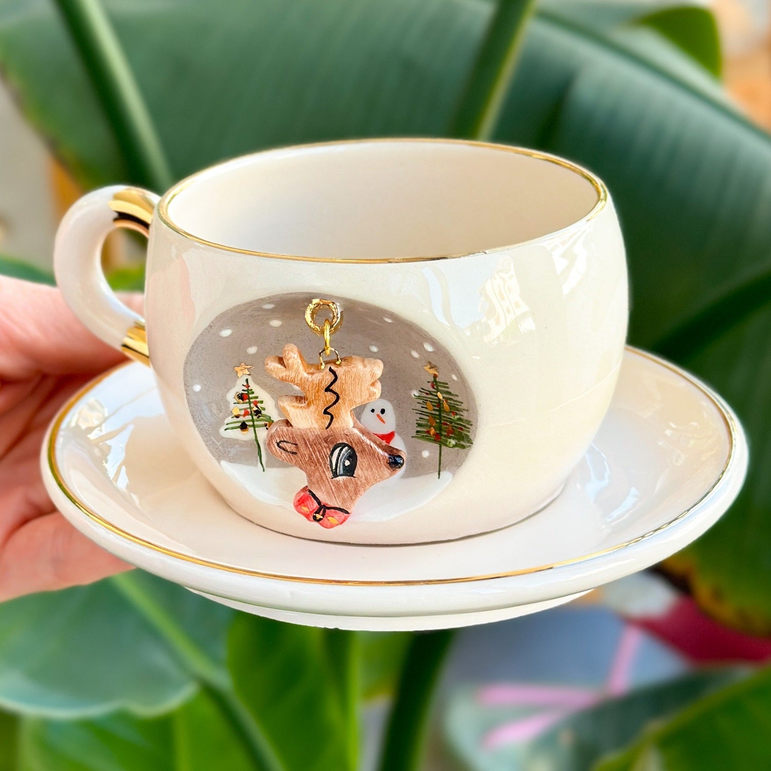 White deer mug with gold trim and reindeer and snowman graphic; matching saucer