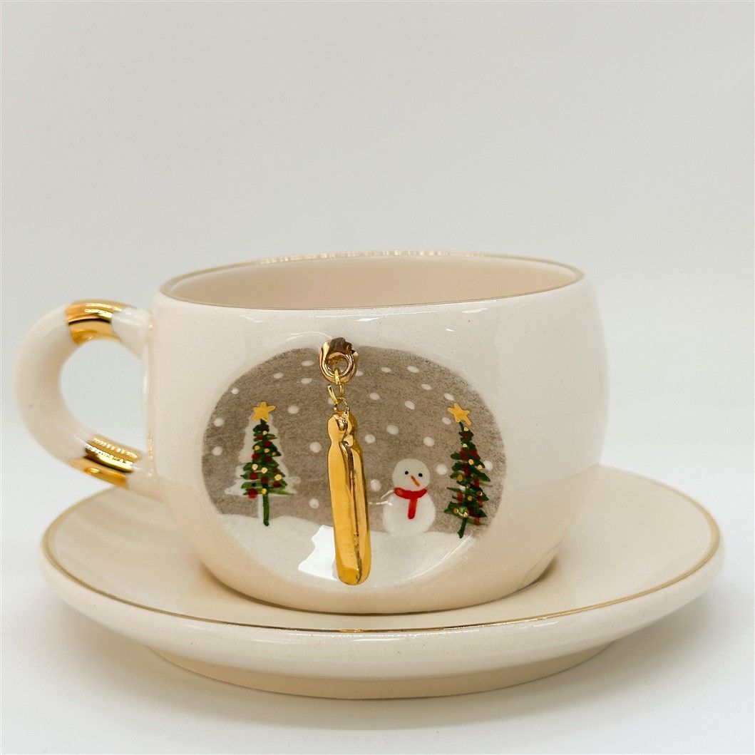 Porcelain tea cup and saucer, white with gold rim and handle; winter I letter motif
