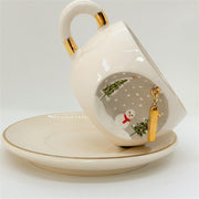 Porcelain tea cup with saucer, gold handle accents, winter letter charm and snowman detail