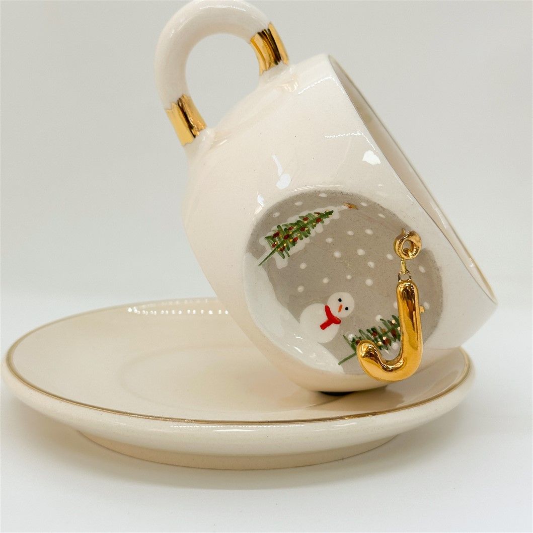 Porcelain tea cup with saucer, gold handle accents, winter letter charm and snowman illustration