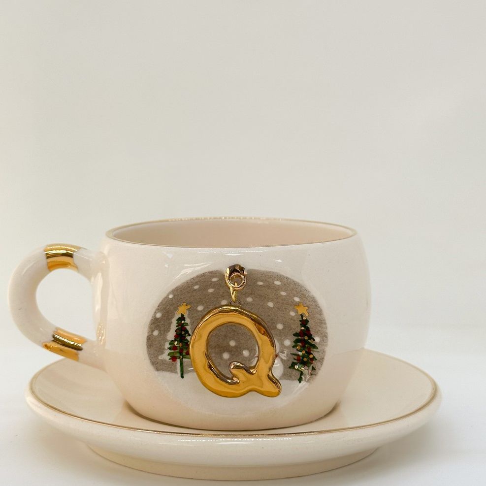 Porcelain tea cup and saucer with gold handle, hanging winter letter charm, trees and snow dots