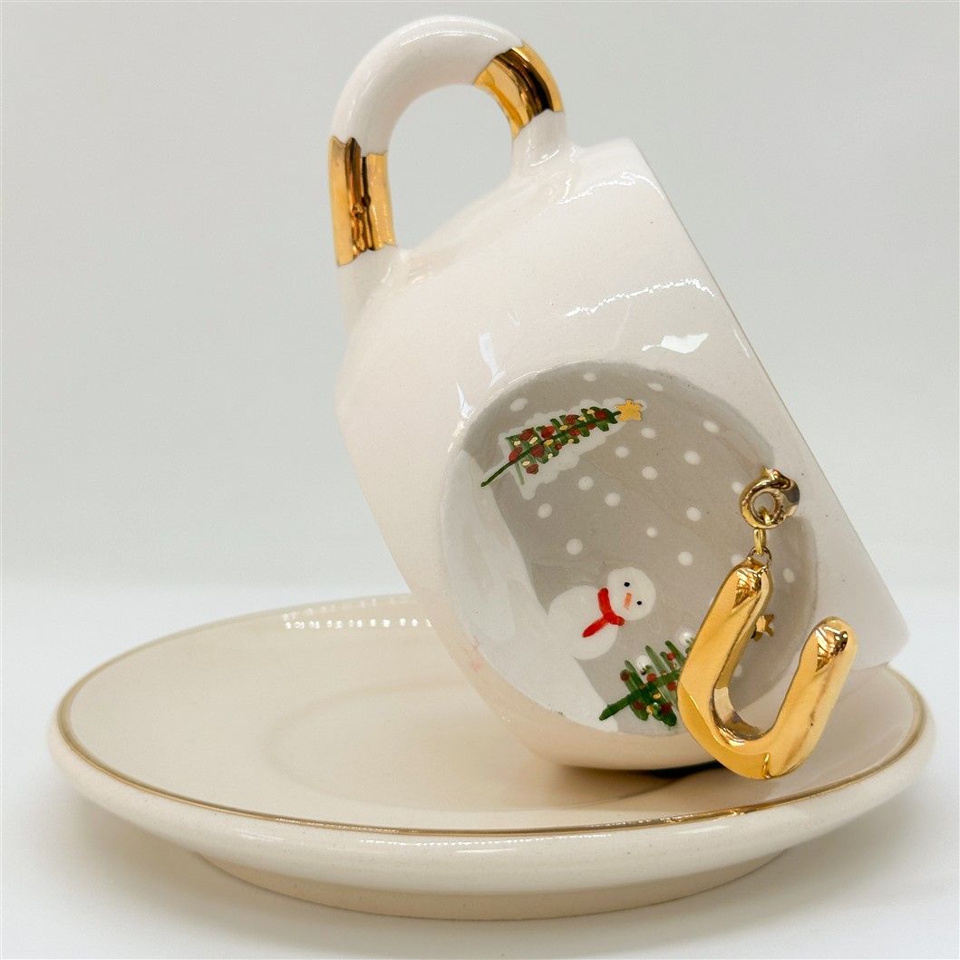 White porcelain tea cup on saucer, gold letter charm with trees and snowman print, 160 ml.