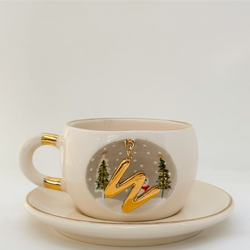 Porcelain tea cup and saucer, white cup with gold letter, trees and snowman graphic, 160 ml.