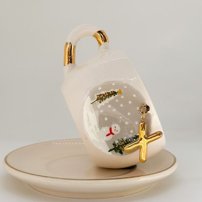 White porcelain tea cup on saucer, gold letter detail, trees and snowman motif, 160 ml.