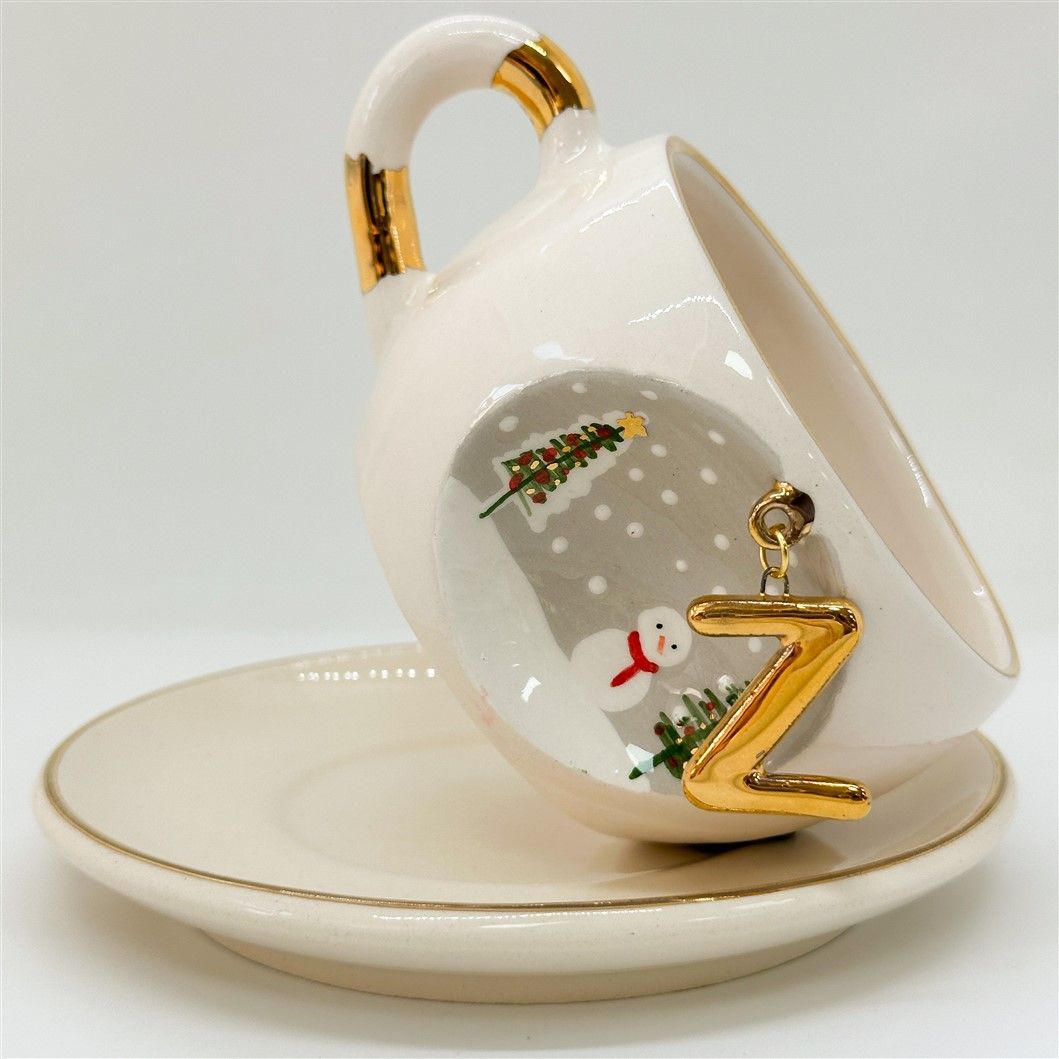 Porcelain tea cup and saucer, white with gold rim and handle; winter Z letter and snowman