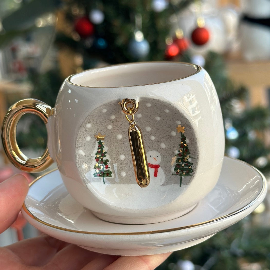 Porcelain coffee cup and saucer with gold letter I charm, snowman and tree scene.