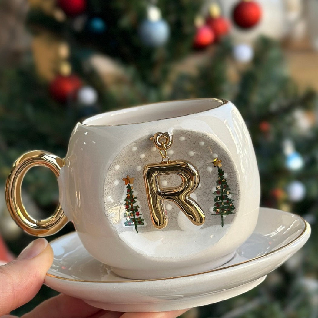 Porcelain coffee cup and saucer with gold letter R charm, snowy trees and snowman.