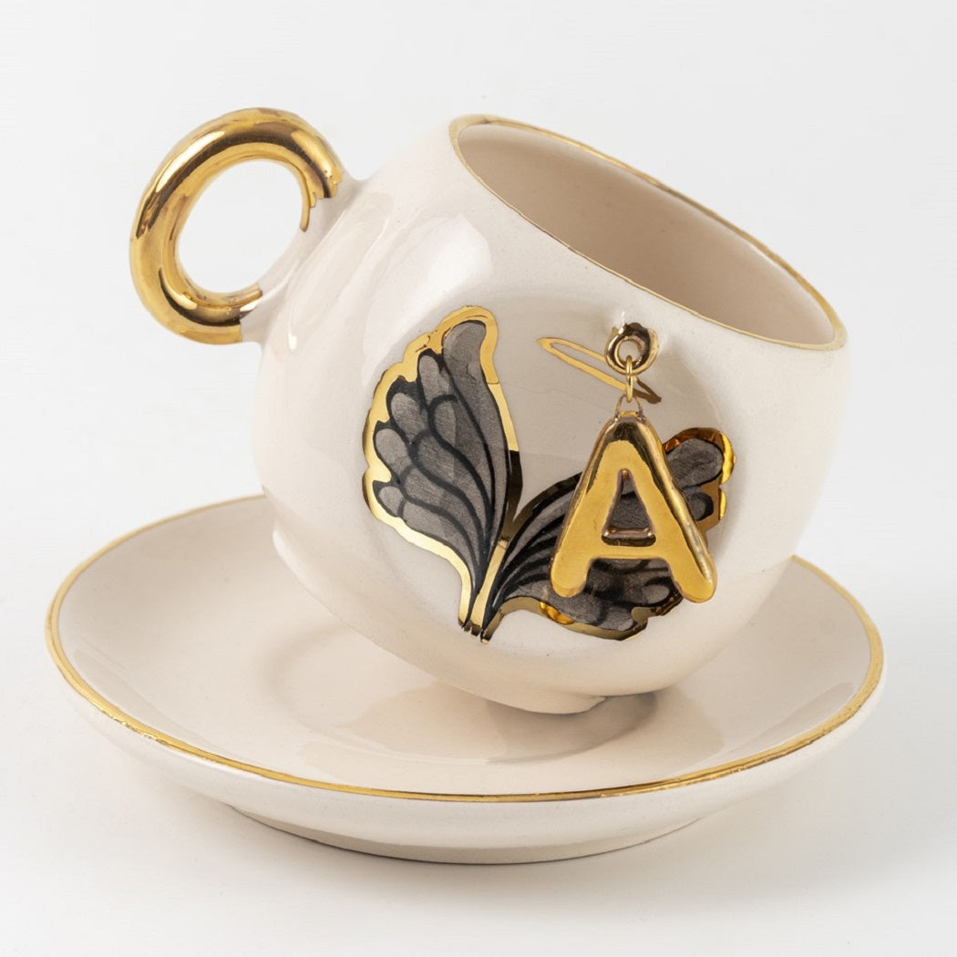 Porcelain cup and saucer with gold handle, angel wing design, letter A accent