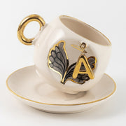 Porcelain cup and saucer with gold handle, angel wing design, letter A accent