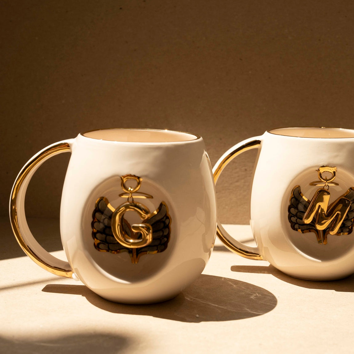 Porcelain mug set of two, white with gold handle and gold letter charm with black wings