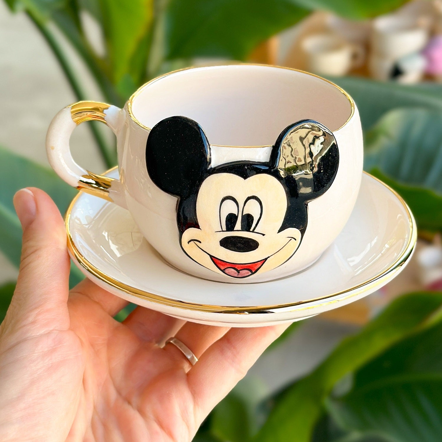 White ceramic tea mug with Mickey Mouse face and gold rim, includes saucer