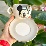 White ceramic tea mug with Mickey Mouse face, gold rim and empty saucer