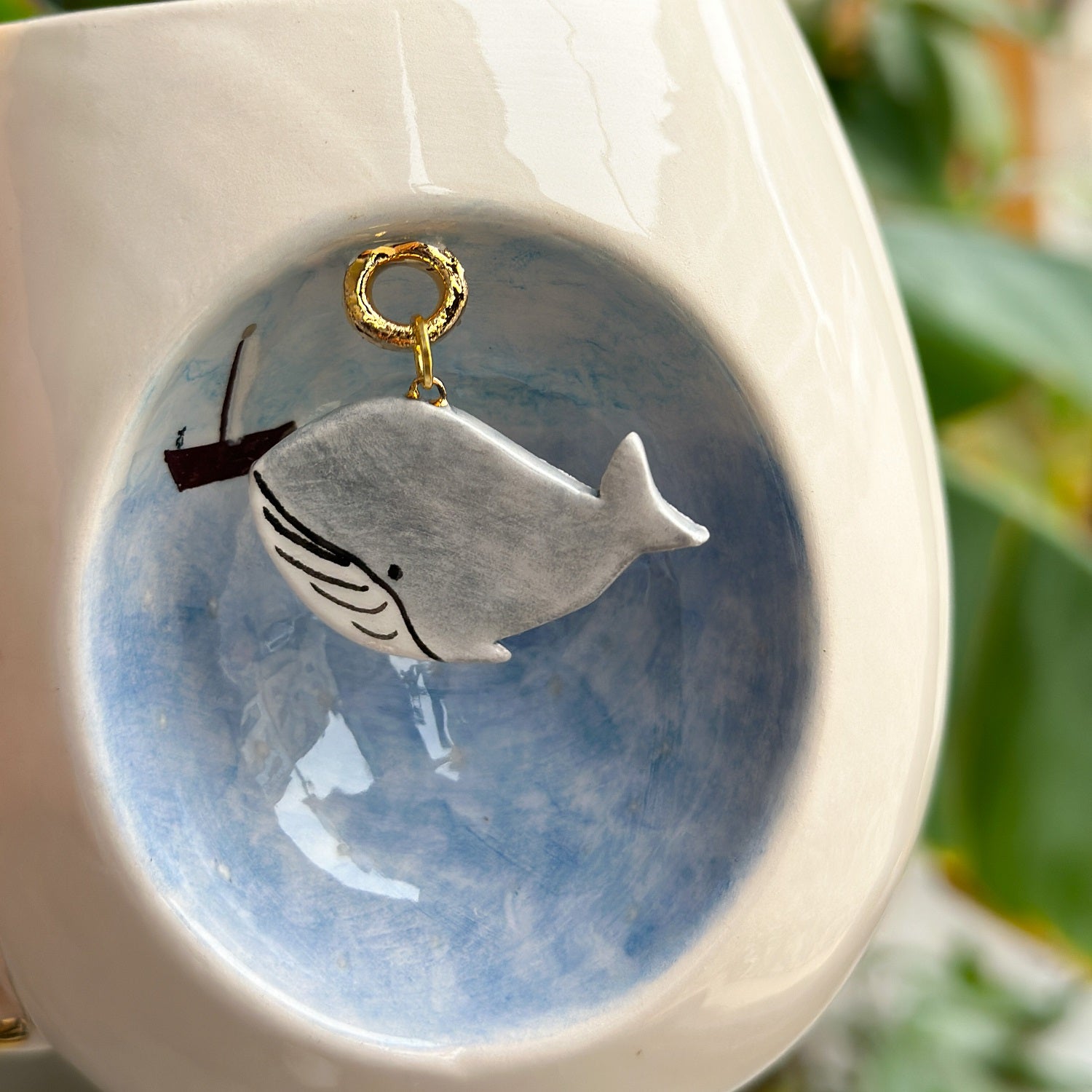 Blue whale mug close-up: gray whale graphic with gold loop on blue background