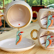 Kingfisher coffee cup with gold rim and handle, white ceramic with bird decal on saucer