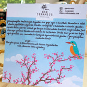 Kingfisher coffee cup with bird-themed info card, pink blossoms and kingfisher illustration