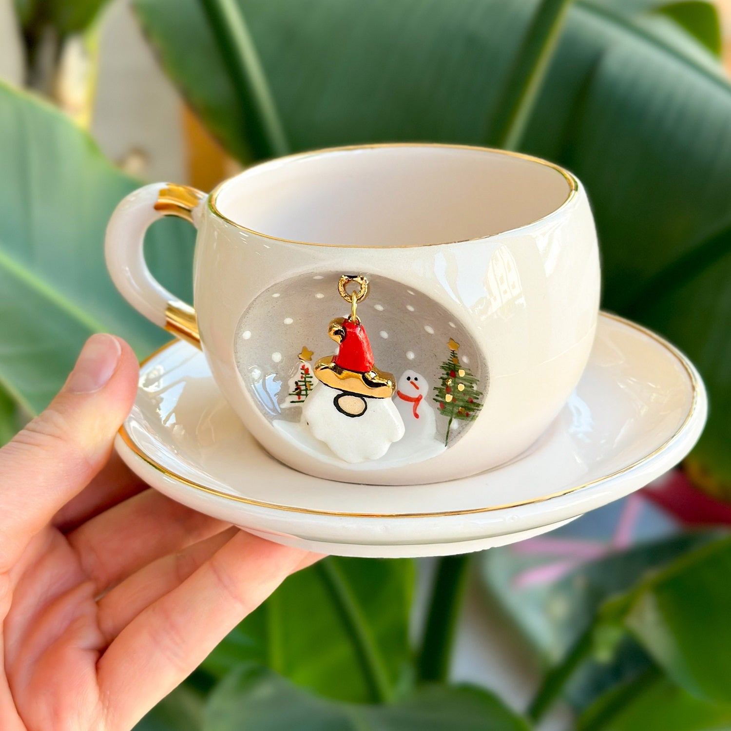 White tea mug on matching saucer with gold trim; Father Christmas charm on front