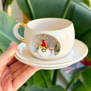 White tea mug on matching saucer with gold trim; Father Christmas charm on front
