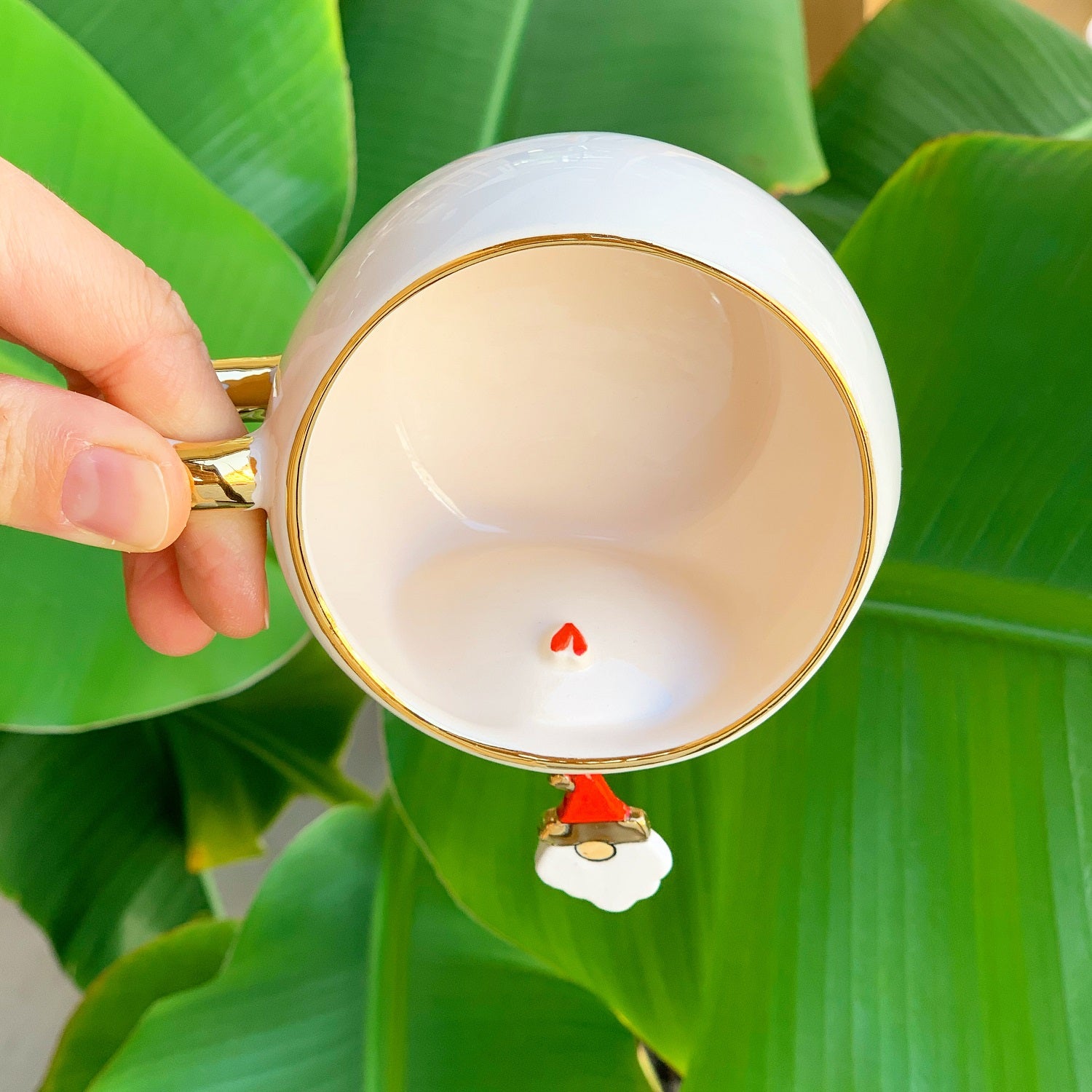 White tea mug interior with gold rim and small Father Christmas charm on underside