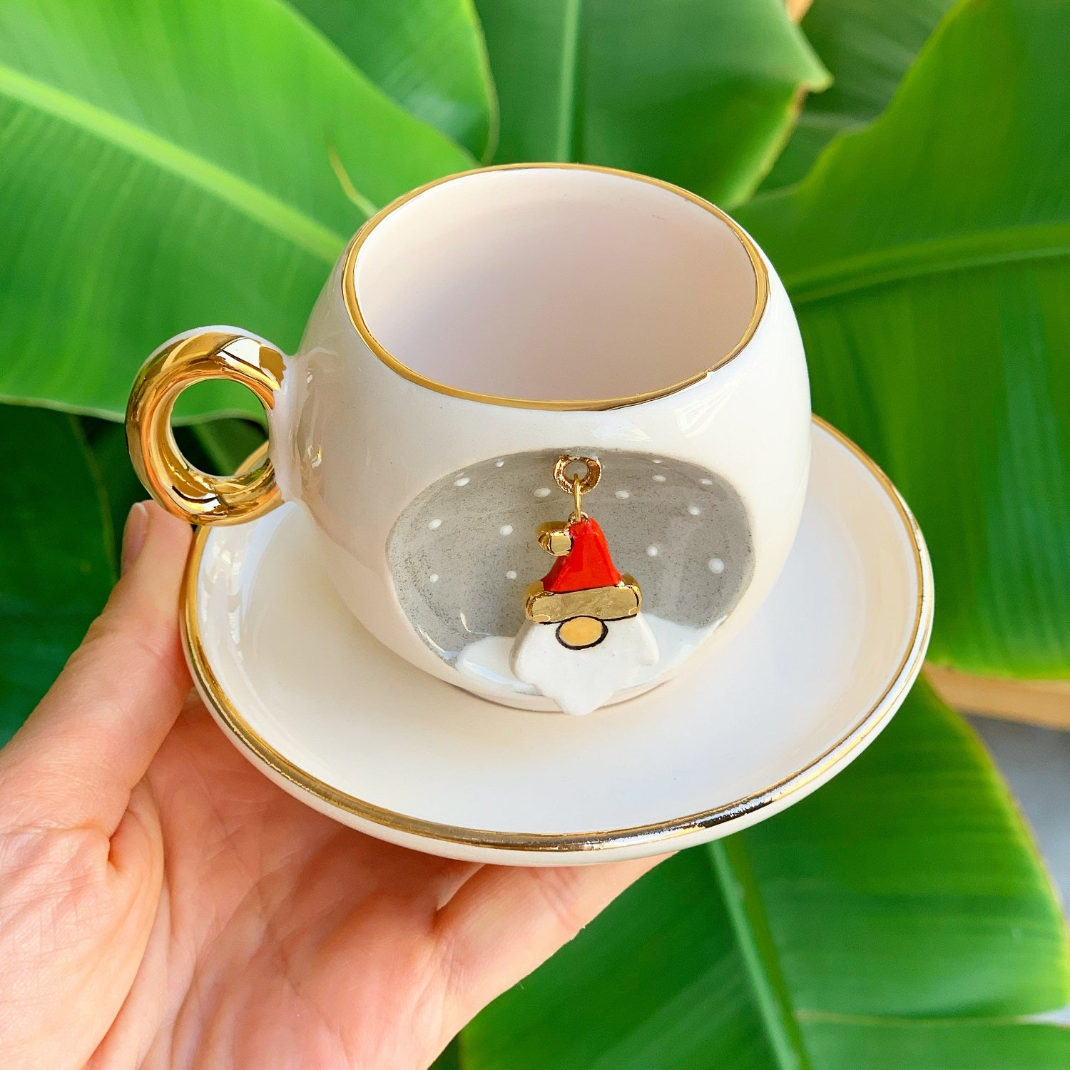Ceramic coffee cup with gold handle, Father Christmas decal inside, on matching saucer